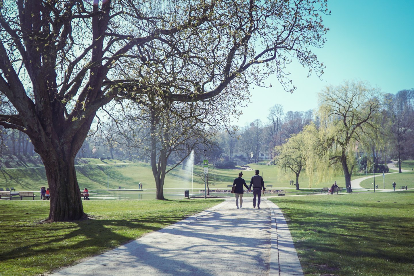 Couple walking hand-in-hand on a park path.
