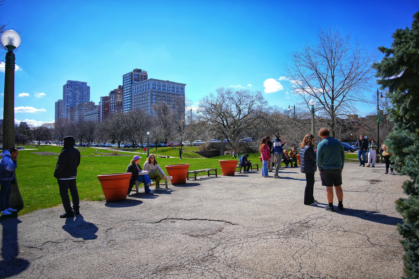 People congregate on a paved path in a city park.
